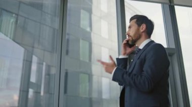 Ofiste konuşan ciddi bir patron şık bir takım elbise giymiş, cep telefonuyla konuşuyor. Stresli iş adamı evde akıllı telefon konuşması yapıyor. Sinir yöneticisi panoramik pencerelerde el kol hareketi yapıyor..