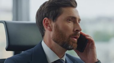 Kendine güvenen iş adamı telefon görüşmesini bitiriyor ve telefon görüşmelerinden memnun olmadığını hissediyor. Modern ofiste oturan takım elbiseli ciddi bir şirket sahibi cep telefonu konuşmasını sonlandırıyor..