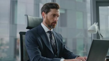 Odaklanmış sakallı yönetmen dizüstü bilgisayarın kapağını kapatmayı bitir. Çekici, ciddi bir yönetici, iş anlaşmasını düşünüyor. Finansal işlem kârlı ortaklık. Yönetici bilgisayarı kapatmakla meşgul.