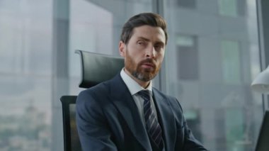 Modern ofiste oturan verileri analiz eden bilgisayar daktilo belgelerinde çalışan profesyonel CEO yöneticisi. Düşünceli sakallı iş adamı dizüstü bilgisayara bakarak şirket planlaması yapıyor. İş konsepti.