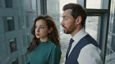 İş arkadaşları modern ofisteki şirket sorunlarından bahsediyorlar. Kendine güvenen iki iş adamı panoramik pencere önünde iş projesini tartışıyor. Odaklanmış iş arkadaşları birlikte çalışıyor.