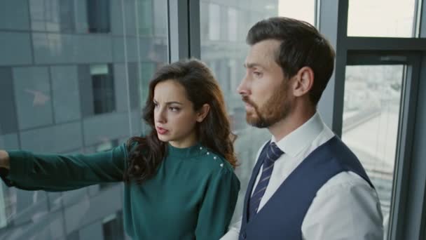 Seriösa Manliga Kvinnliga Kollegor Kommunicerar Företagets Strategi Stående Vid Kontorsfönstret — Stockvideo