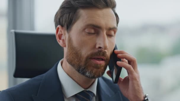疲れた髭のオフィスマネージャーが悪いニュースを閉じるのを聞いてスマートフォンを話しています 電話会話で顧客の苦情を聞く会社の従業員 失望した気分に見えるビジネスマンは強調した — ストック動画