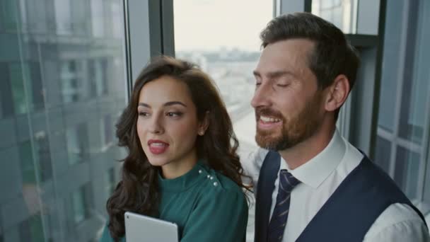 Szczęśliwa Para Partnerów Biznesowych Rozmawia Radośnie Stojąc Przy Oknie Panoramicznym — Wideo stockowe