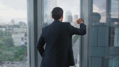 Gergin, düşünceli bir yönetici ofis penceresinin yanında duran şık takım elbiseli şirket krizinden endişeleniyor. Kendine güvenen sakallı iş adamı iş başarısızlığını düşünüyor finansal kaybı şirket temerrüdü