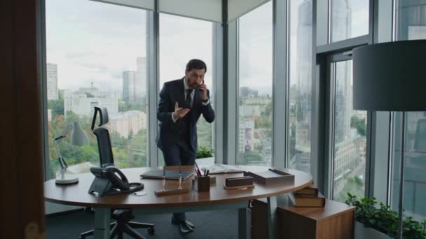 怒っているビジネスマンは 現代のオフィスに立って電話を終了します 中高年の神経起業家がスマートフォンで叫んでいる 仕事の失敗に感情的に反応する不満ビジネスマン 会社の危機 — ストック動画