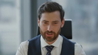 Kendine güvenen gülümseyen koç video toplantısında konuşuyor. Ofise yakın oturuyor. Çekici sakallı iş adamı müşterileriyle çevrimiçi konferans yoluyla iletişim kuruyor. Kendine güvenen yönetici meslektaşlarına veda ediyor.