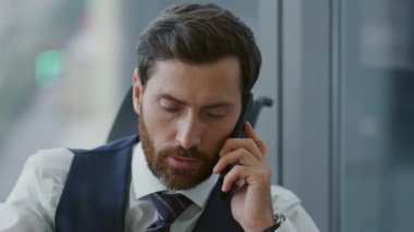 Modern şirket ofisinde oturan ciddi bir patron telefona cevap veriyor. Orta yaşlı sakallı iş adamının portresi akıllı telefondan iş süreçleri hakkında konuşuyor. Cep telefonuyla yönetici danışmanlığı.