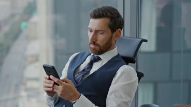 Kendine güvenen yönetmen ofiste cep telefonu ekranını izliyor. Ciddi patron endişe verici iş sorunları düşünüyor. İnternet 'te iş meselelerinde sörf yapan stresli profesyonel yönetici.