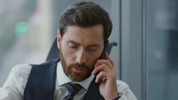 現代の会社のオフィスに座っている電話に真剣に答える上司が閉じます ビジネスプロセスについてスマートフォンで話す中年の髭のビジネスマンの肖像画 携帯電話によるマネージャーコンサルティング — ストック動画