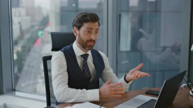 Neşeli sakallı danışman müşterilerle internette konuşuyor. Gülümseyen yönetici internet kamerasıyla modern ofiste danışmanlık yapıyor. Kendinden emin iş adamı görüntülü konuşma ile uzaktan iletişim kuruyor.