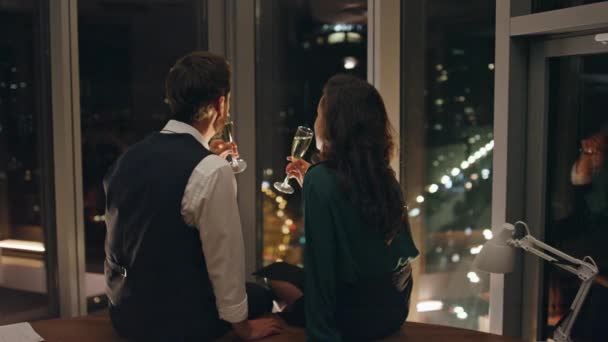 迷人的男人诱惑着调情的女人一起喝香槟庆祝成功的计划 情侣们谈情说爱 坐在全景窗前欣赏夜景 浪漫的概念 — 图库视频影像