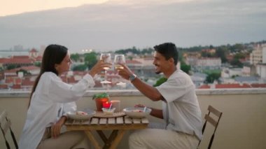 Gün batımı terasında kutlama yapan pozitif bir çift. Mutlu aile balayı tatilinde şampanya içerek kadeh tokuşturur. Karı koca, otelde alkolün tadını çıkarıyor.