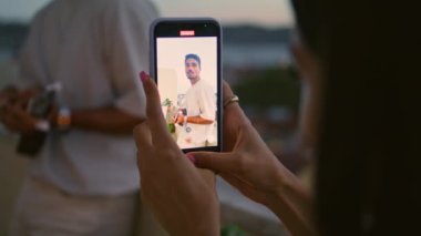 Kadın, erkek akşam balkonunun video kaydını yapıyor. Yakındaki çift hafta sonu birlikte dinleniyor. Kız silueti ukulele müzik dinleyip film çekiyor. Rahat adam gün batımı terasında gitar çalıyor.