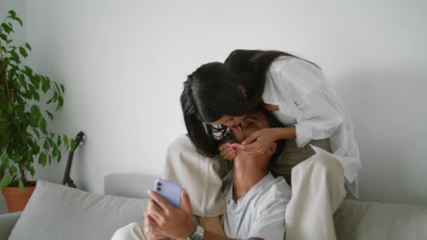 Lachende Frau Küsst Mann Auf Couch Nahaufnahme Ehepaar Schaut Smartphone — Stockvideo