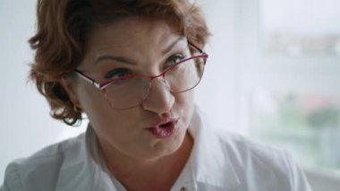 Profesyonel kozmetik uzmanı bilinmeyen bir hastayla konuşurken gülümsüyor. Güzellik prosedürlerini açıklayan kadın yaklaşıyor. Gözlüklü orta yaşlı estetisyen. Müşterilere güzellik danışmanlığı yapıyor..