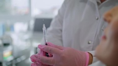 Bilinmeyen profesyonel kozmetolog güzellik kliniğinde içinde ilaç vitaminleri olan bir şırınga hazırlıyor. Sertifikalı güzellik uzmanı, gençleştirme yüz gerdirme ameliyatları için hazırlık yapıyor..