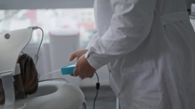 Yüz tedavisi uygulayan tanınmamış profesyonel kozmetik uzmanı modern klinikte kadınların yüzüne maske takıyor. Güzellik uzmanı fototerapi kullanarak cilt tazeleme yapıyor. Estetik düzeltme kavramı.