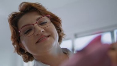 Gözlüklü gülümseyen doktor. Kadının yüzü, keçeli kalemle düzeltme çizgileri çiziyor. Olgun bir kozmetik uzmanı, olgun bir müşteriyi yaşlanmayı önleyici iğneler için hazırlıyor. Prosedür kavramı kaldırılıyor.