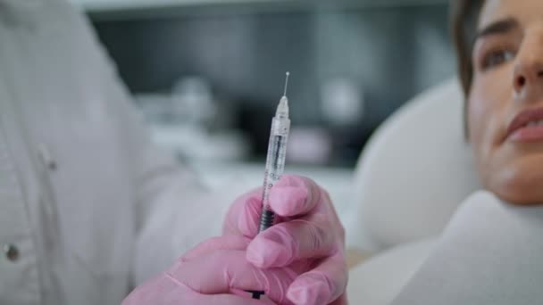医生手拿着用胶原蛋白做的医用注射器 在注射女性病人之前要面对着自己的近视 临床上不知名的粉红手套美容美发药师 — 图库视频影像