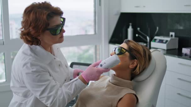 美容师在美容院为妇女制定抗衰老程序 现代激光治疗使皮肤光滑健康 经认证的皮肤科医生应用仪器疗法治疗面部更新 — 图库视频影像