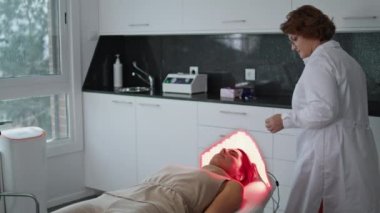 Güzellik kliniğinde cilt yenilenmesi için modern kozmetik fotodinamik tedavi. Profesyonel kozmetik uzmanı kurşun lambalarla fototerapi ekipmanlarını ayarlıyor. Spa salonunda yaşlanma karşıtı cilt bakımı