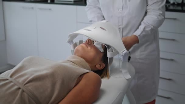 Nieznany Kosmetolog Wykonujący Zabieg Pielęgnacji Skóry Włączający Specjalną Maskę Led — Wideo stockowe