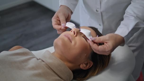 Kosmetolog Wkłada Okulary Ochronne Twarz Kobiety Leżącej Komfortowo Klinice Kosmetycznej — Wideo stockowe
