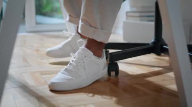 Modern apartmanın kapanış koltuğunda oturan isimsiz serbest çalışan. Afrika kökenli Amerikalı iş adamı ayakları içeri tek başına giriyor. Beyaz ayakkabılı adam hafif ev ofisinde arka koltukta kayıyor. Uzak çalışma konsepti 