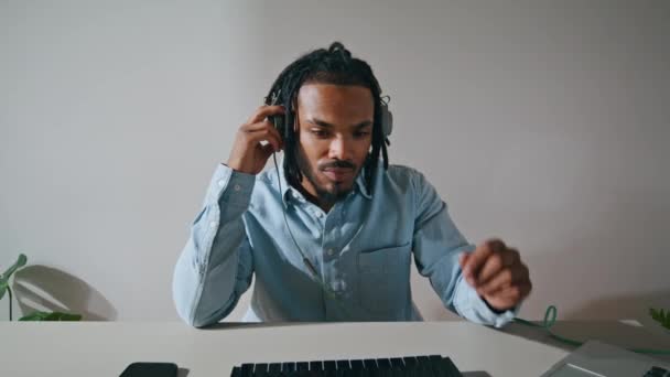 在室内听耳机的黑头发男人放大了 集中制作人欣赏灯光桌旁的音乐 非裔美国人自由职业者混合电子轨道在远程工作室 职业概念 — 图库视频影像