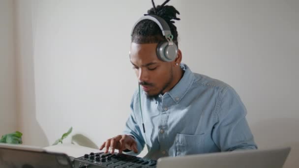 当代编曲者创作轨道公寓特写 灵感来自音乐制作人触动了看起来像笔记本电脑的Midi键盘 非裔美国人耳机使用控制器音响设备工作室 — 图库视频影像