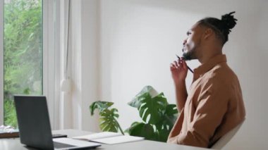 Düşünen iş adamı iş yerinde fikirler yazıyor. Çalışmayı düşünen bir adam. Not defterine not alan düşünceli bir adam. Afrikalı Amerikalı serbest yazar günlük defterine planlar çiziyor. 
