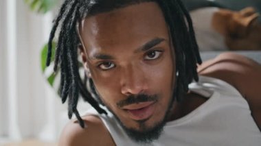 Siyah saçlı adam ev portresi. Tatmin olmuş adam yakın plan bir şaheser çiziyor. Gülümseyen rastalı ressam, rahat bir dairede çizim yaparken görülüyor. Afrikalı Amerikalı ressam iç atmosferde yaratıyor.