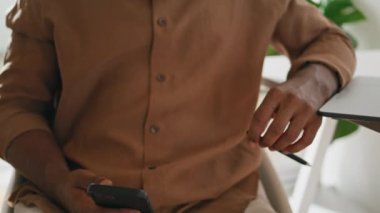 Odaklanmış adam, yakın çekimde akıllı telefon gibi görünüyor. Dehşet saçan adam mesaj okuyor. Telefonun hareketli görüntüsünü izliyor. Afrikalı Amerikalı serbest çalışan modern dairede cep telefonu haberleri alıyor. Uzak çalışma 