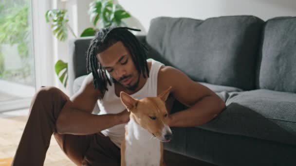 投标者在家里的特写镜头里宠物狗 一个人在时髦的公寓里独自享受与家畜相处的时光 真是令人毛骨悚然 非洲裔美国人在客厅里爱抚他的狗朋友 — 图库视频影像