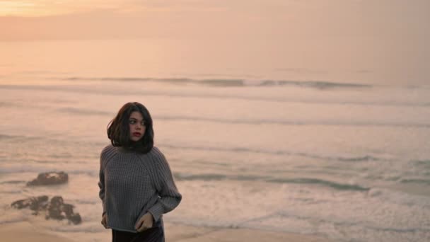 寂寞浪漫的女孩独自站在平静的海浪旁 享受着多云的海景 迷人的年轻女子穿着灰色的毛衣站在阴暗的海滨 严肃的自然造型 傍晚时分 — 图库视频影像