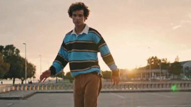 Handsome guy training longboard outdoor closeup. Young man learning skateboarding on urban background. Focused skater enjoying on city street. Curly teenager spending summer. Youth sports concept 