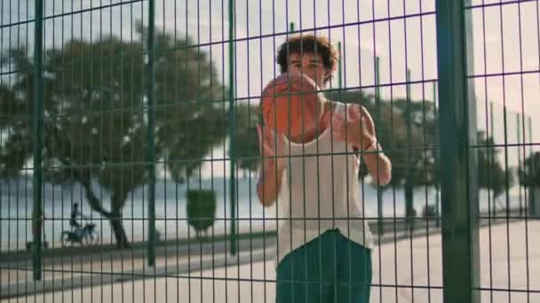 スタジアムの背景のクローズアップで現代的なティーンスピニングボール指 オープンエアの遊び場で遊んでいる若い男 バスケットボール選手は カメラの肖像画を探してスキルを示す スポーツアクションコンセプト — ストック動画