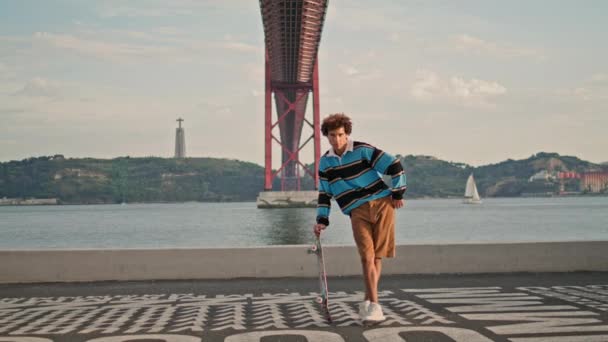 Sportive Guy Posing Skateboard Embankment Hipster Standing River View Skater — Vídeo de stock