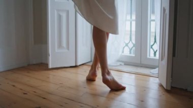 Barefoot girl feet moving at cozy apartment close up. Unrecognizable woman dancing on laminate floor. Young lady legs having fun enjoying morning at home. Anonymous person relaxing near big window