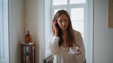 Relaxed girl walking at morning flat closeup. Calm woman sipping coffee at luxury apartment. Lovely lady crossing home drinking tea. Beautiful female person enjoying leisure time at cozy house