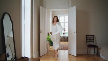Cheerful woman running morning apartment alone. Emotional girl having fun at cozy flat close up. Positive lady dancing at comfortable house. Relaxed housewife enjoying weekend at domestic interior