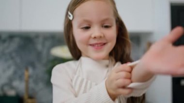 Funny child rolling sleeves up at kitchen portrait. Little girl preparing making dough with mother indoors closeup. Cute baby in apron having fun baking at home. Junior chef helping in cook room