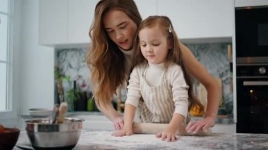 Şirin anne çocuğu içeri yakın plan çekimde hamur topluyor. Sevgi dolu anne kız mutfakta hamur işi yoğurarak birbirine bağlanıyor. Sevimli bir kız ebeveyne yardım ediyor. Kadın çocuk evde yemek yapıyor. Gelenekler konsepti