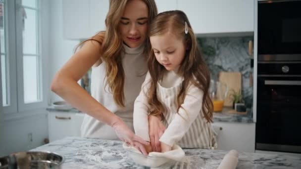 妈妈的女儿把面团放在室内烘烤 在厨房里照料孩子的女人 可爱的小女孩帮助父母 妈妈的孩子在家一起做饭 家庭概念 — 图库视频影像