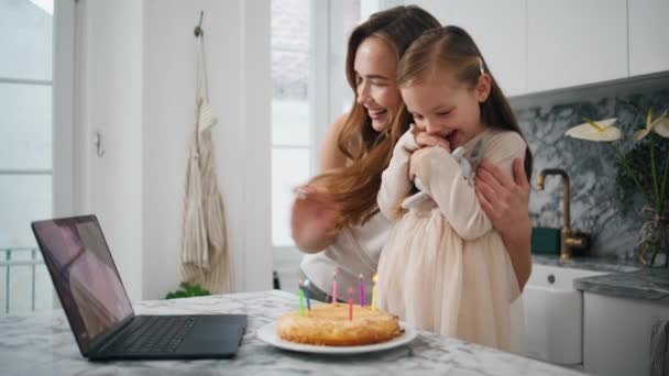 儿童生日录像所有庆祝特写 在虚拟笔记本电脑聊天中微笑的女人问候丈夫 温柔的母亲在厨房拥抱女儿 抱着玩具准备吹蜡烛的小女孩 — 图库视频影像