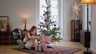Noel ağacının yanında şirin bir aile hediye kutusu sallıyor. Şefkatli anne ve meraklı çocuk sıcak bir yere bakıp zum yapıyor. Noel süslemeli evinde kızı kucaklayan olumlu bir kadın. Yeni yıl konsepti