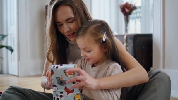 好奇的婴儿打开礼物在新年的房子关门 快乐的妈妈把兔子玩具送给可爱的女儿 母亲和小孩在室内圣诞树旁玩乐 关爱家庭庆祝活动 — 图库视频影像