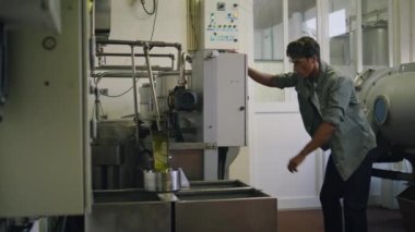 Kumaş kapanışında basın makinesine dönüşen ciddi bir adam. Manufactory 'da ekstra bakir zeytinyağı üreten profesyonel bir işçi. Odaklanmış yetişkin adam sadece soğuk baskı fabrikasının iç kısımlarını kontrol ediyor.