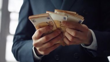 Unknown businessman counting euro bills denomination of fifty close up. Man hands holding pack of european currency indoors. Elegant manager calculating money cash. Business financial profit concept.